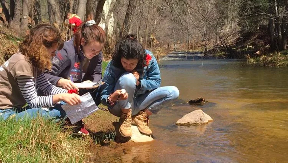 Student teams examining water by river Student teams examining water by river